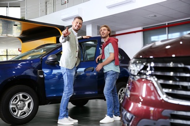 Salesman with customer in modern car dealership