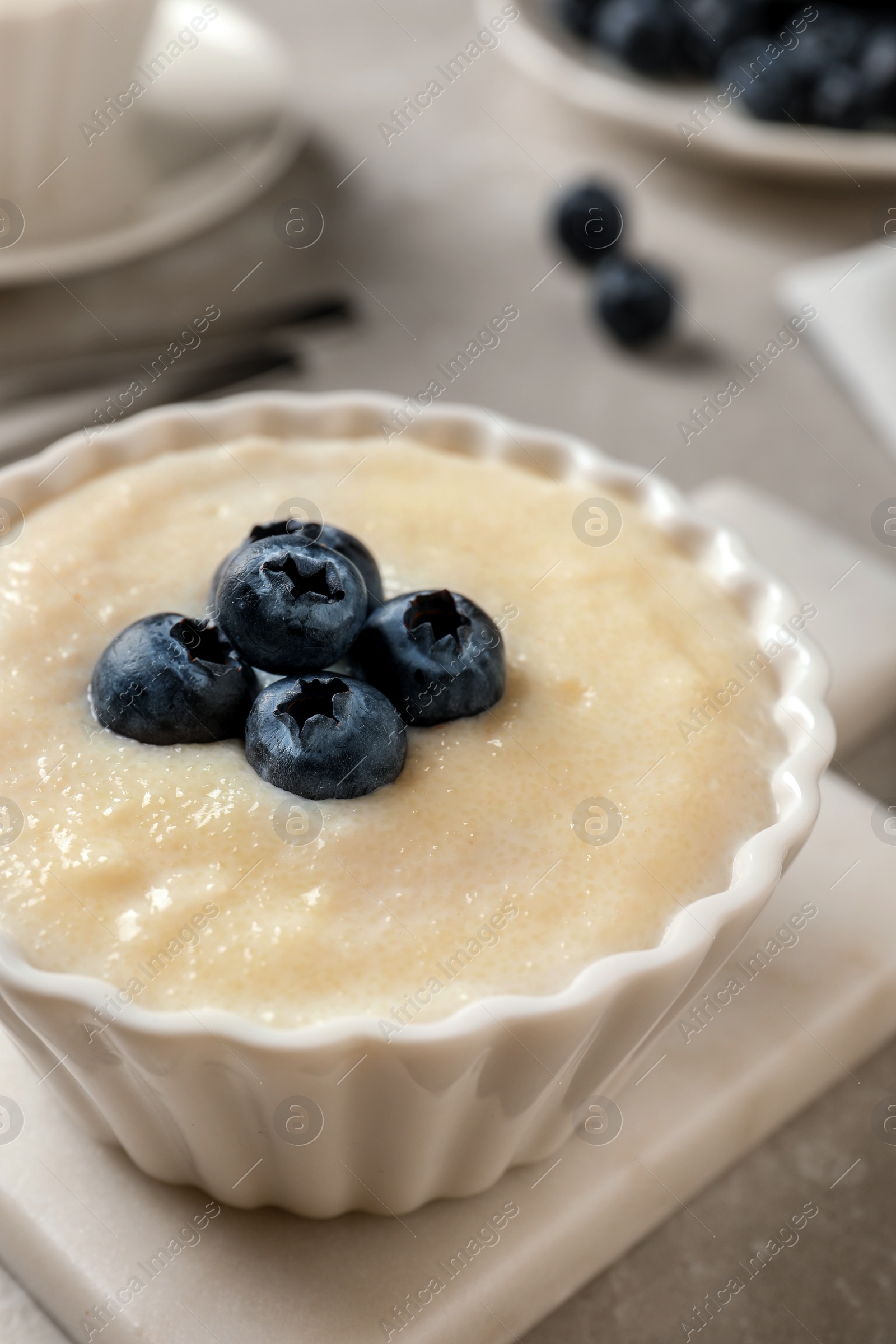 Photo of Delicious semolina pudding with blueberries on white table, closeup