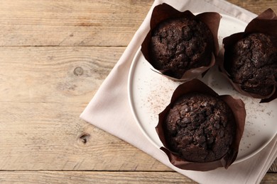 Photo of Tasty chocolate muffins on wooden table, top view. Space for text