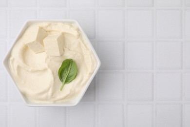 Delicious tofu sauce and basil leaf in bowl on white tiled table, top view. Space for text