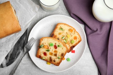 Photo of Delicious cake with candied fruits and milk on light grey table, flat lay