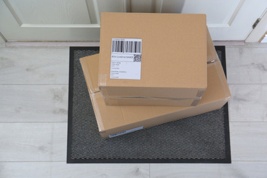 Photo of Cardboard boxes on rug near door, top view. Parcel delivery service