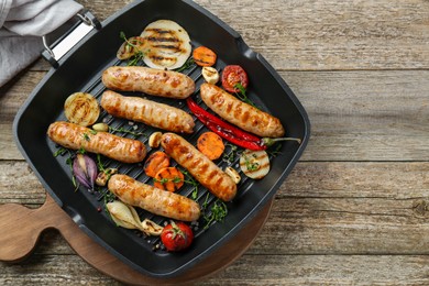 Photo of Tasty fresh grilled sausages with vegetables on wooden table, flat lay. Space for text