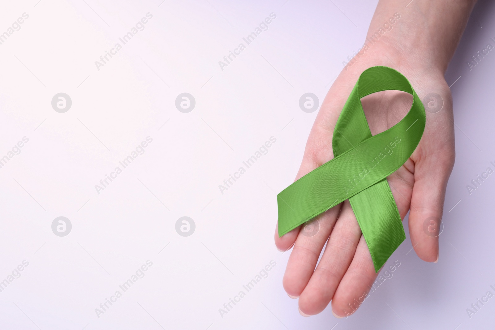 Photo of World Mental Health Day. Woman holding green ribbon on white background, top view with space for text