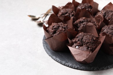 Photo of Tasty chocolate muffins on light table, closeup. Space for text