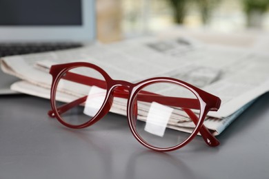 Photo of Newspapers and glasses on grey table, closeup