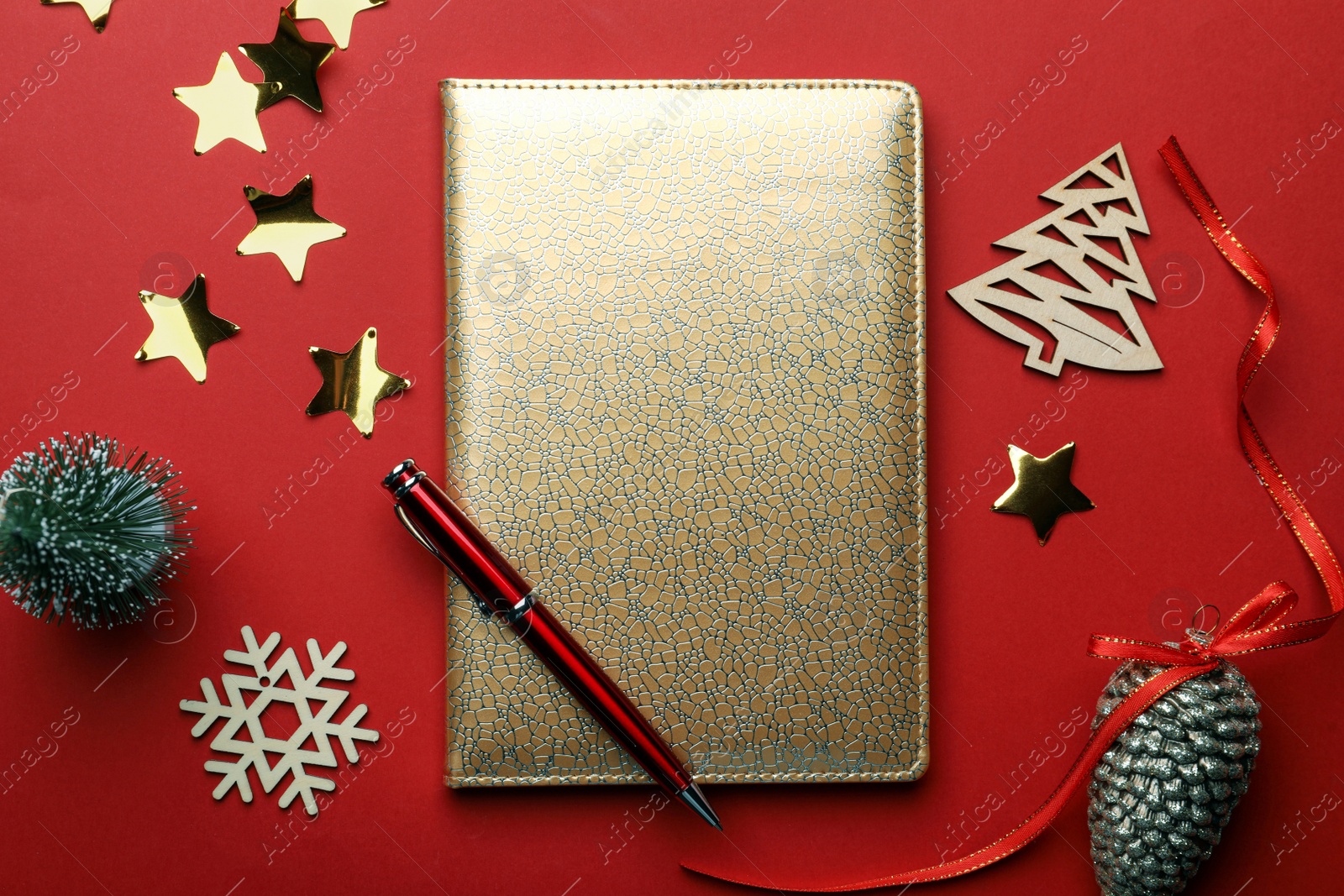 Photo of Golden planner and Christmas decor on red background, flat lay