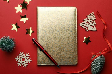 Golden planner and Christmas decor on red background, flat lay