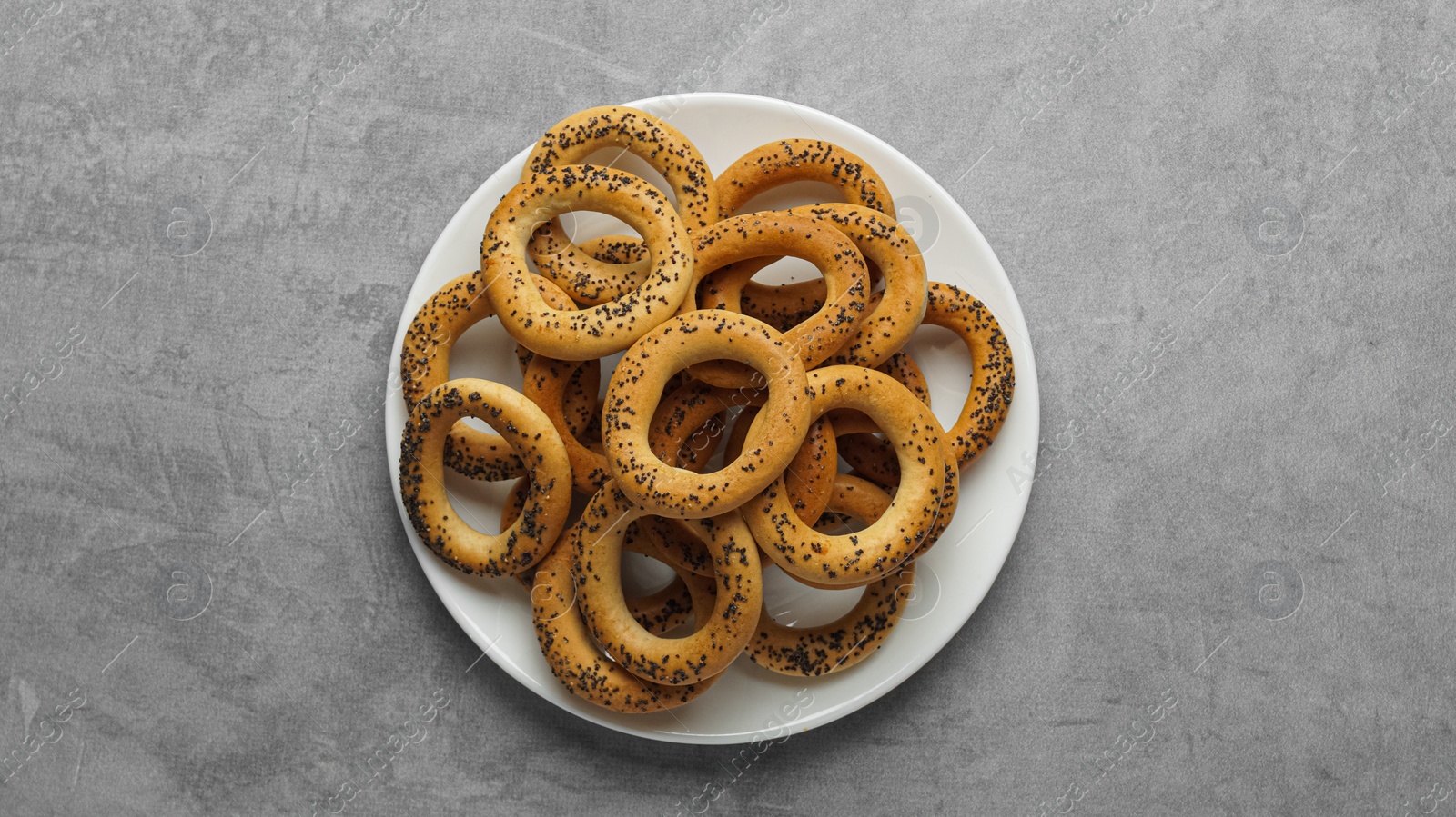 Photo of Plate with delicious ring shaped Sushki (dry bagels) on light grey table, top view