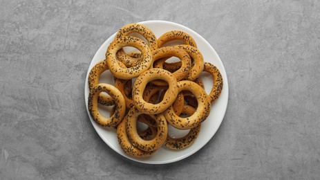 Plate with delicious ring shaped Sushki (dry bagels) on light grey table, top view