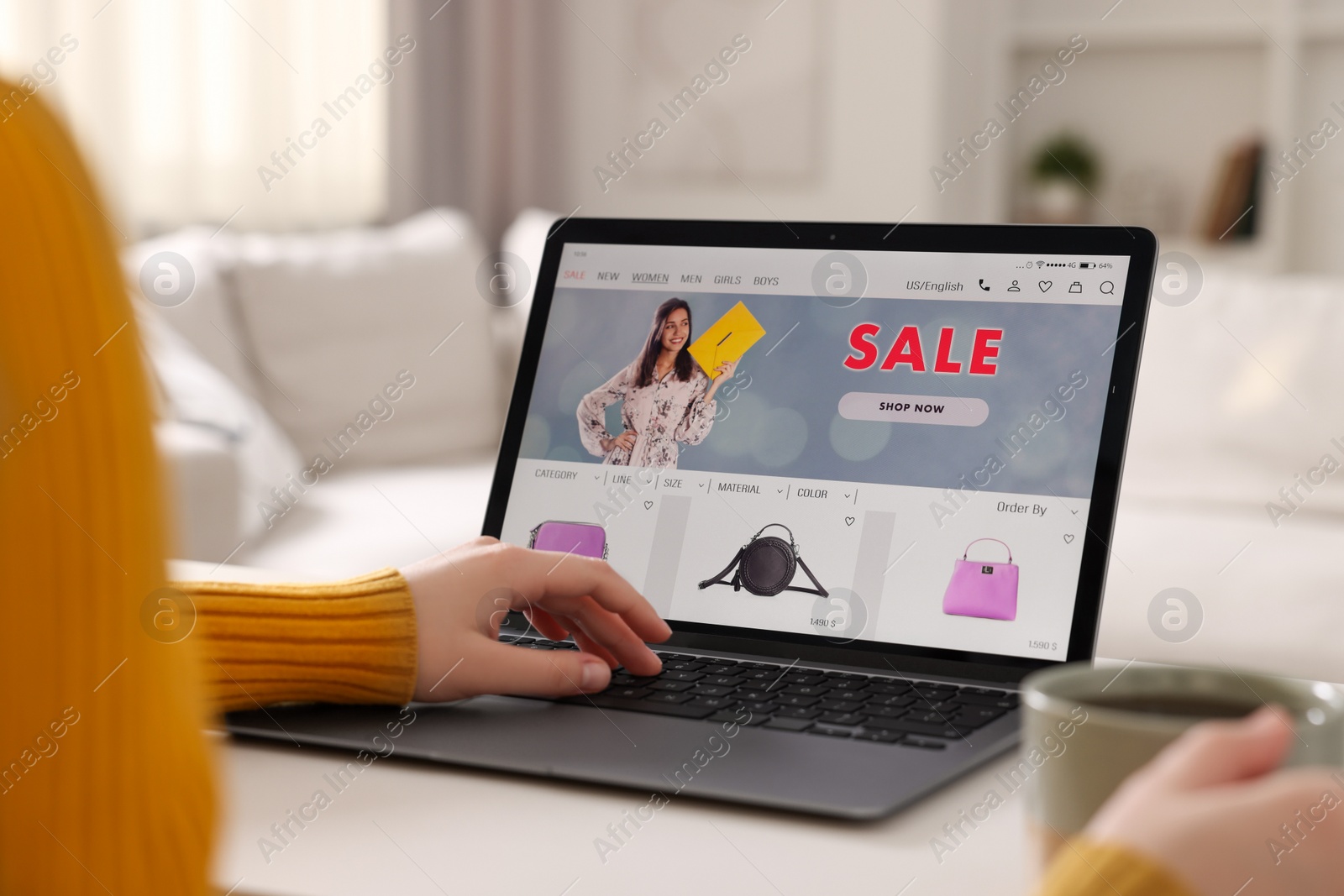 Photo of Woman with cup of tea shopping online during sale on laptop at home, closeup