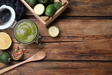 Feijoa jam and fruits on wooden table, flat lay. Space for text