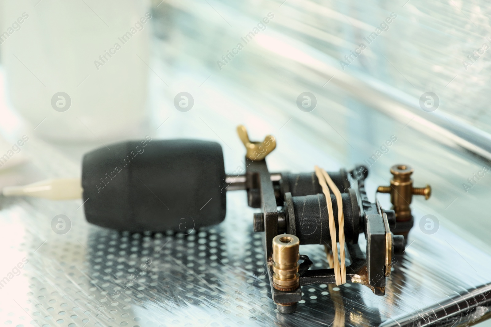 Photo of Modern professional tattoo machine on table in salon