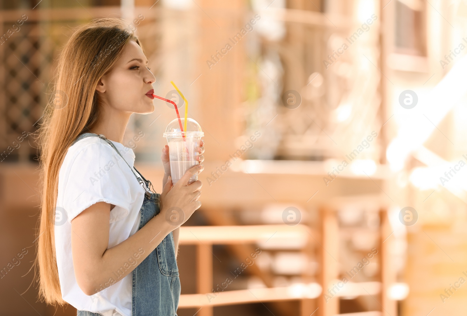 Photo of Young woman with cup of delicious milk shake outdoors