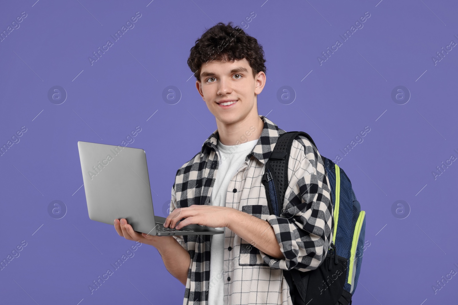 Photo of Portrait of student with backpack and laptop on purple background