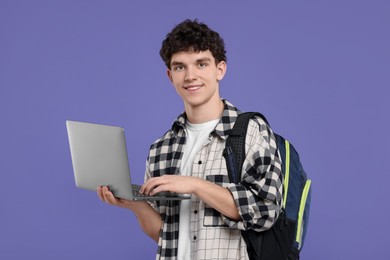 Photo of Portrait of student with backpack and laptop on purple background