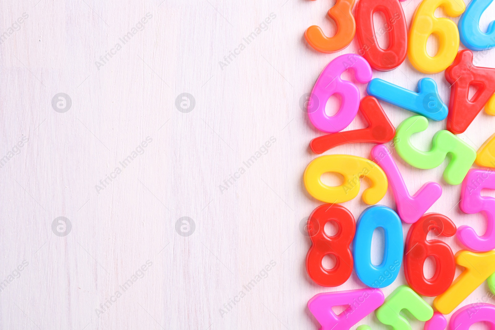 Photo of Colorful numbers on white wooden school desk, flat lay. Space for text