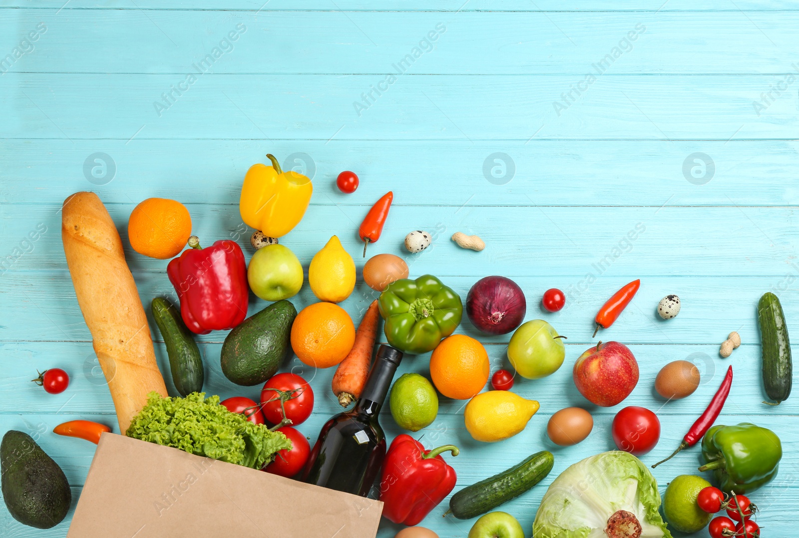 Photo of Flat lay composition with overturned paper bag and groceries on blue wooden background