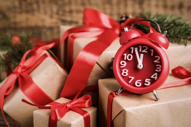 Alarm clock and Christmas gifts on wooden background, closeup. Boxing day