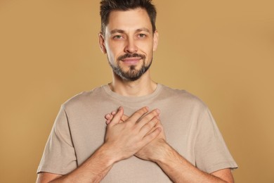 Photo of Man with clasped hands praying on beige background