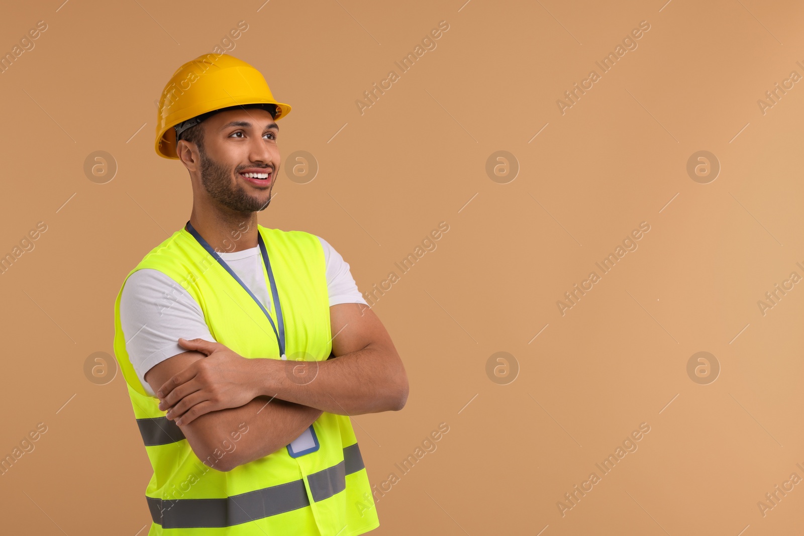 Photo of Engineer with hard hat and badge on beige background, space for text