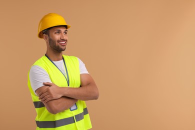 Engineer with hard hat and badge on beige background, space for text