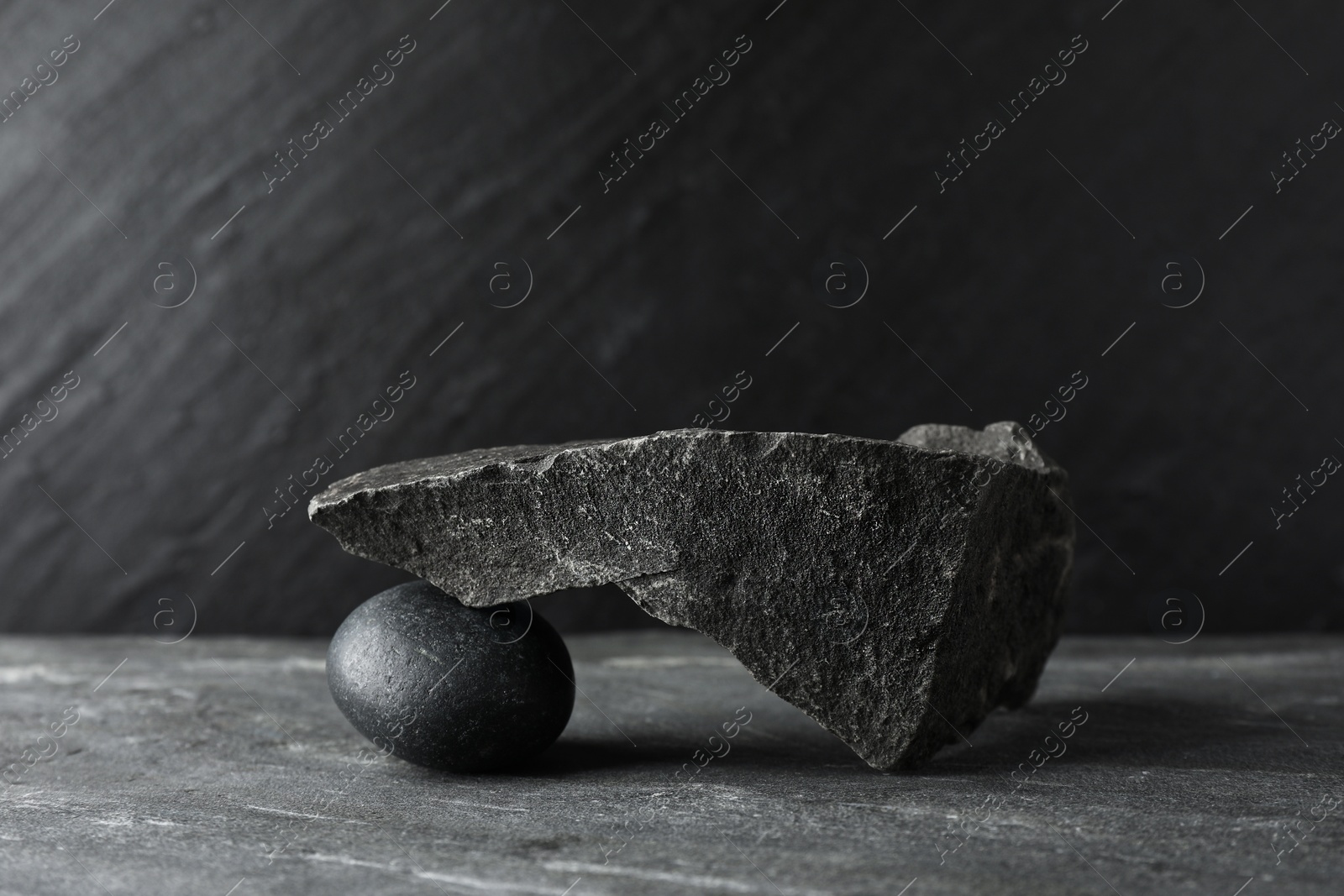 Photo of Presentation for product. Podium made of different stones on grey textured background. Space for text