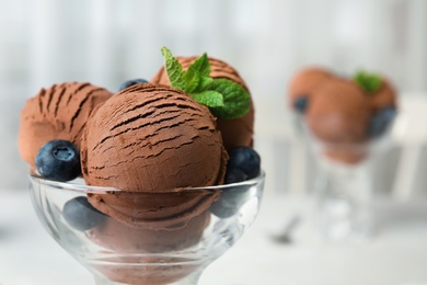 Photo of Glass bowl of chocolate ice cream on blurred background, closeup with space for text