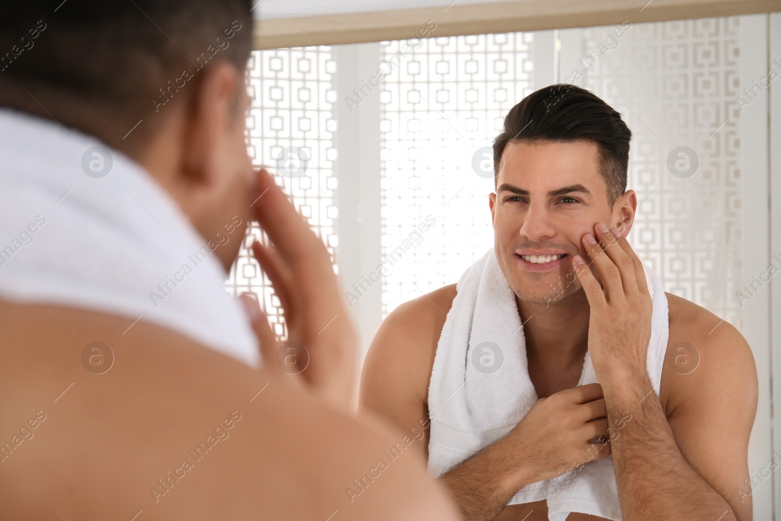 Photo of Handsome man with towel near mirror in bathroom