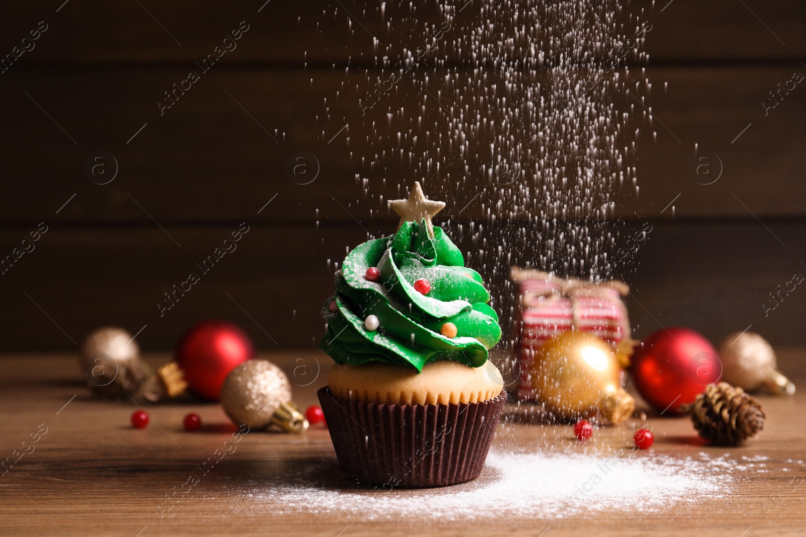 Photo of Sprinkling powdered sugar on Christmas tree shaped cupcake