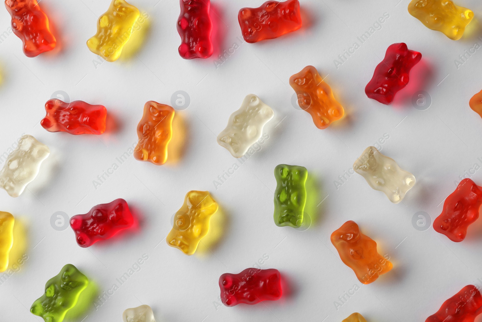 Photo of Delicious color jelly bears on white background, top view