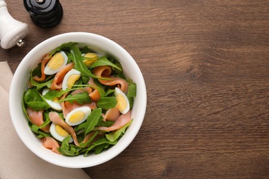 Delicious salad with boiled eggs, salmon and arugula on wooden table, flat lay. Space for text