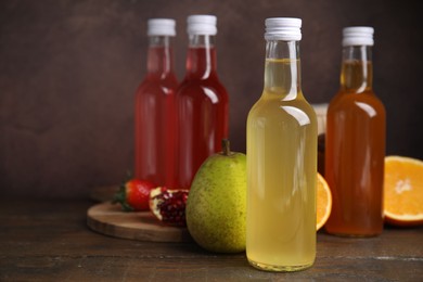 Photo of Delicious kombucha in glass bottles and fresh fruits on wooden table