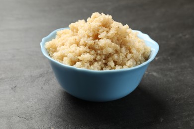 Tasty quinoa porridge in bowl on black textured table