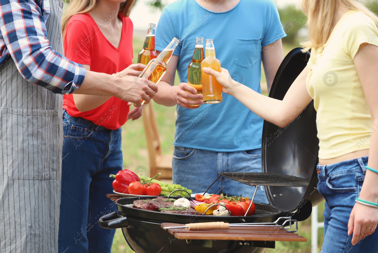 Photo of Young people having barbecue with modern grill outdoors