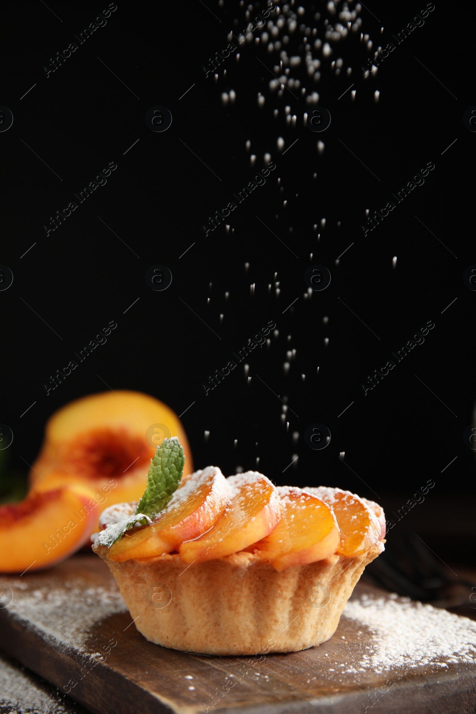 Photo of Decorating delicious peach dessert with powdered sugar on wooden board