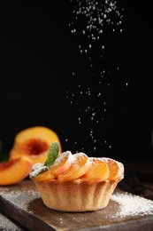 Photo of Decorating delicious peach dessert with powdered sugar on wooden board