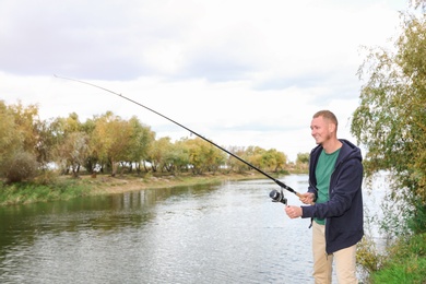 Man with rod fishing at riverside. Recreational activity