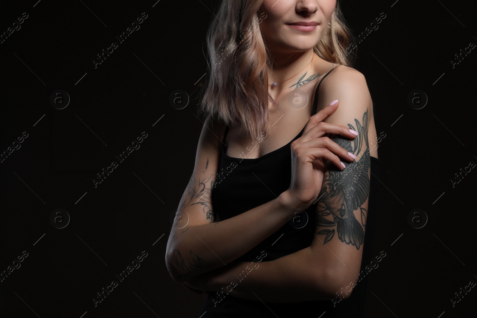 Photo of Beautiful woman with tattoos on body against black background, closeup. Space for text