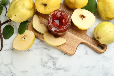 Delicious quince jam and fruits on white marble table, flat lay