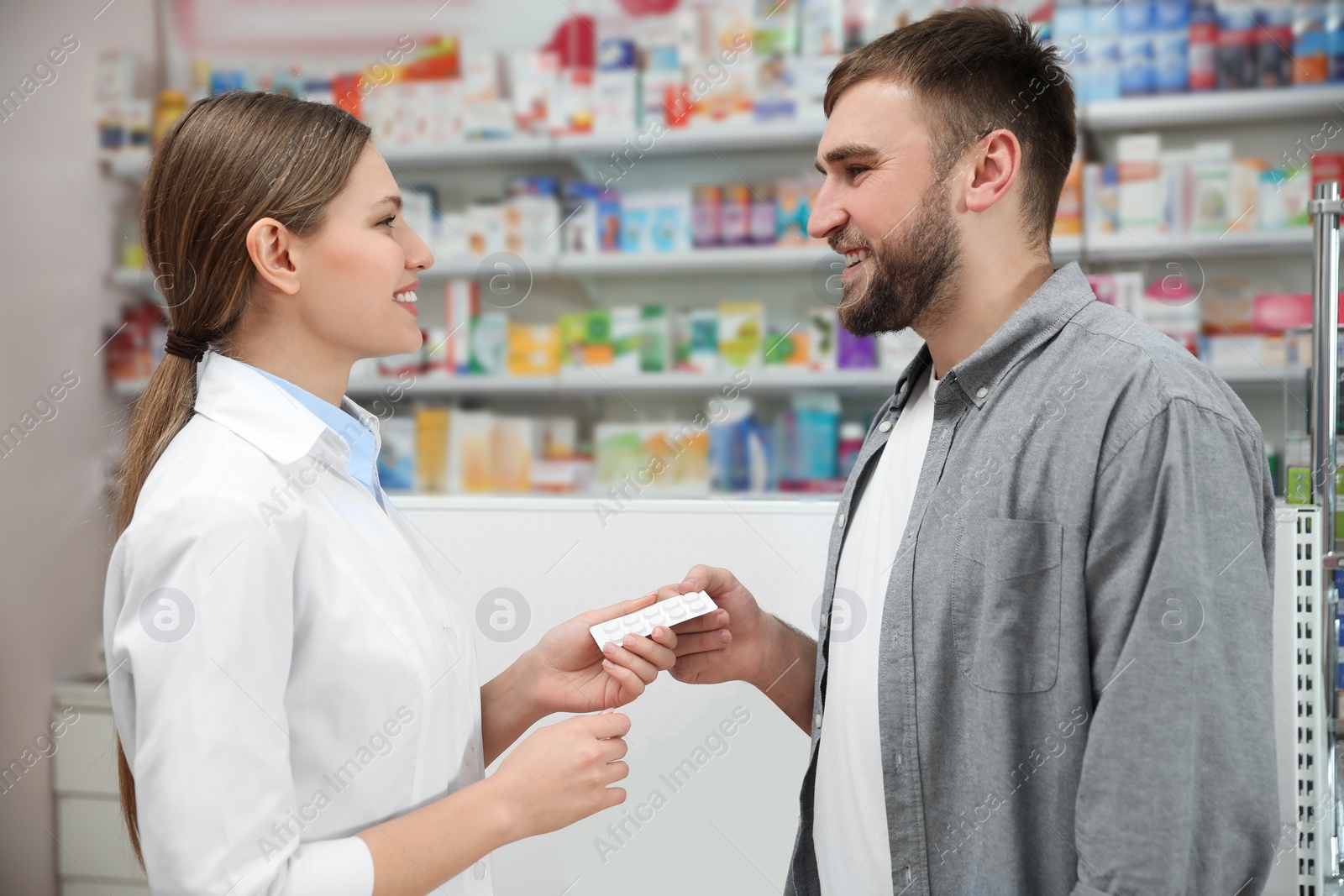 Photo of Professional pharmacist giving pills to customer in modern drugstore