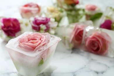 Photo of Ice cubes with flowers on marble background, closeup. Space for text