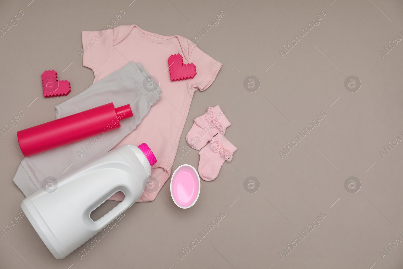 Photo of Bottles of laundry detergents, baby clothes and decorative hearts on grey background, flat lay. Space for text