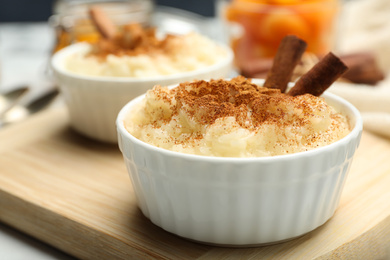 Photo of Delicious rice pudding with cinnamon on wooden board, closeup