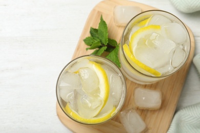 Glasses of cocktail with vodka, ice and lemon on white wooden table, top view