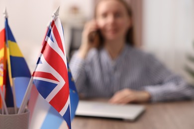 Woman talking on smartphone at table indoors, focus on different flags