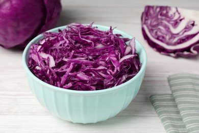 Photo of Tasty fresh shredded red cabbage in bowl on white wooden table