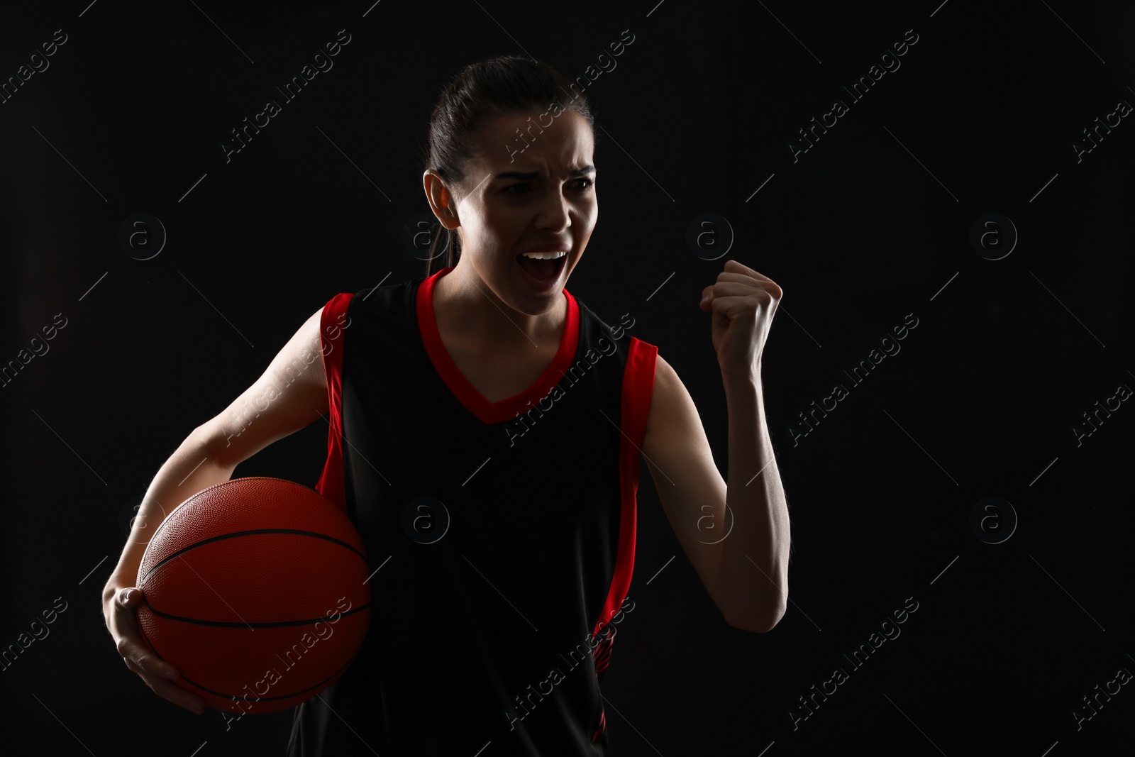 Photo of Basketball player with ball on black background