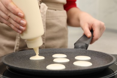 Photo of Woman cooking cereal pancake on frying pan, closeup