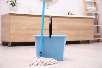 Photo of Mop and plastic bucket in bathroom. Cleaning floor